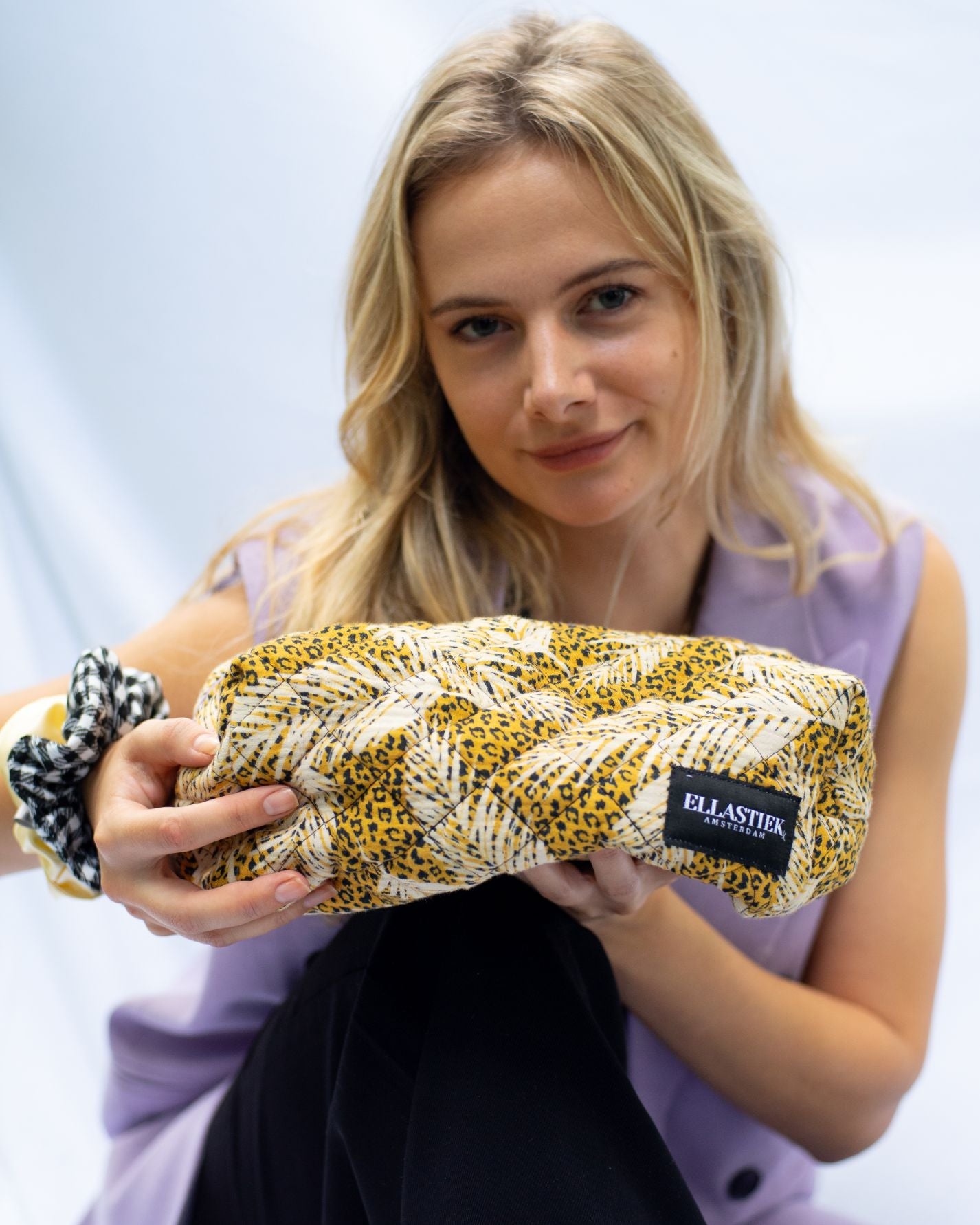 Ellastiek een model met panter en verenprint make-up tas inn haar handen en diverse scrunchies